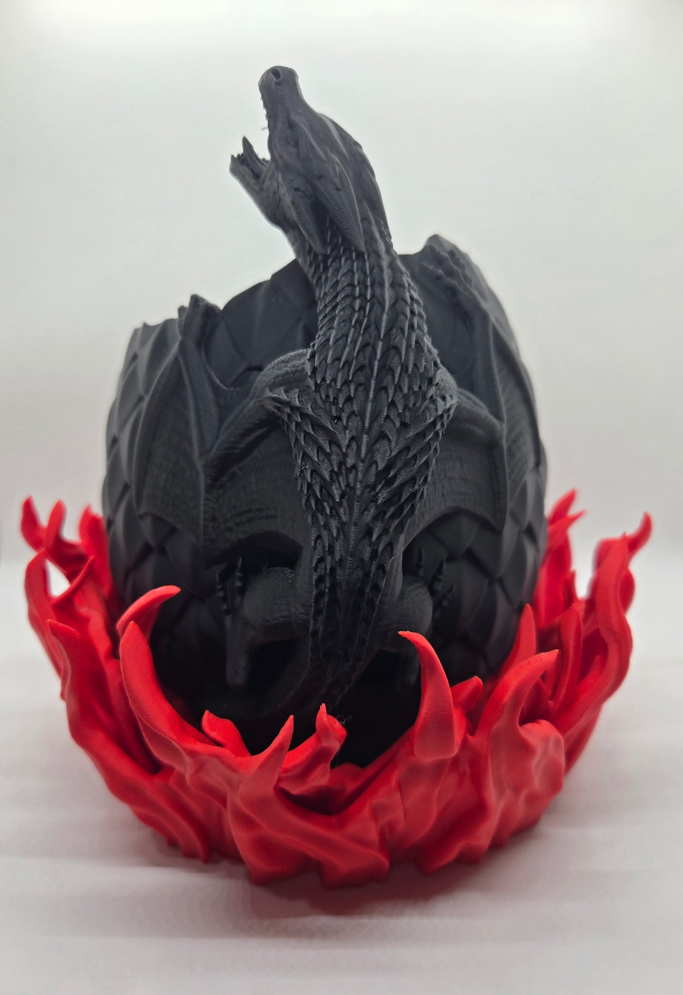 "3D printed dragon egg planter with flame base"

"Fantasy-themed plant pot with dragon coiled around egg"

"Dragon egg flower pot – black egg and red flames"